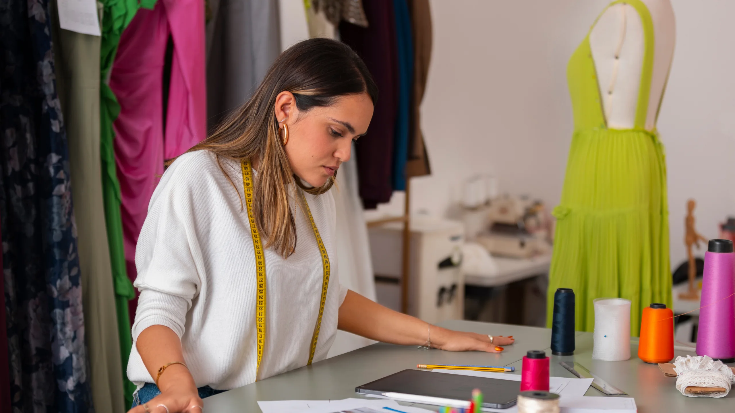 Tailor measuring fabric for a custom design in a studio.