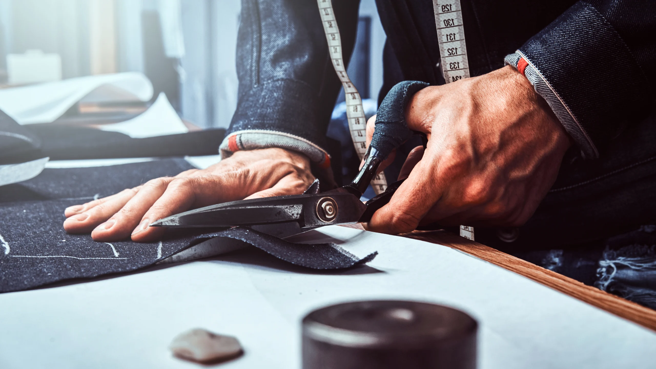 Tailor cutting fabric with scissors during bespoke suit making