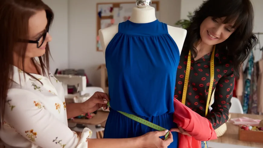 Tailors performing a complex alteration by measuring a blue dress on a mannequin