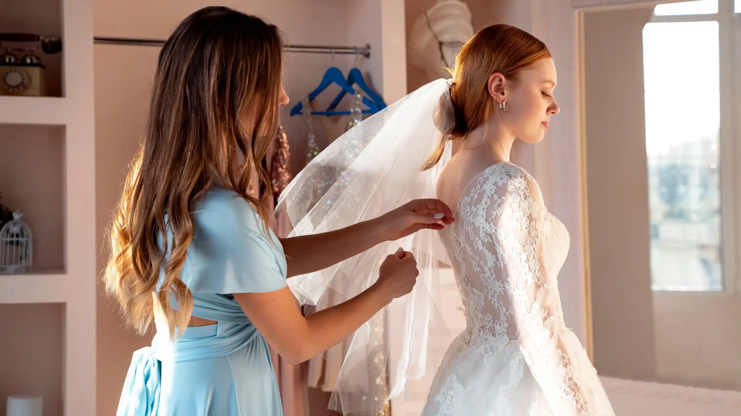 bridesmaid adjusting veil on bride in wedding dress alterations