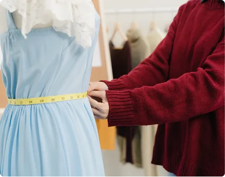 Tailor measuring a woman's dress for clothing alteration