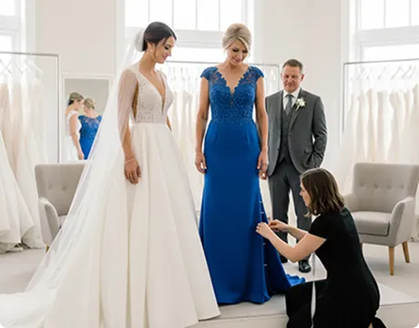 Tailor adjusting mother of the bride dress during professional fitting for wedding